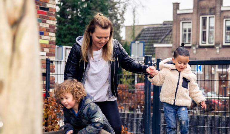 pedagogisch medewerker en twee jongentjes spelen buiten 