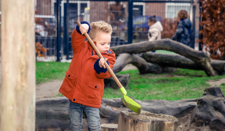 Kindje met een schep bij de kinderopvang.