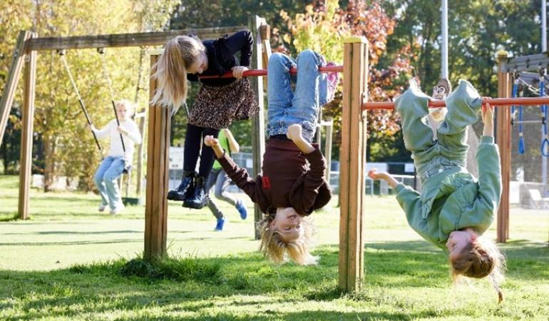Drie meisje ondersteboven aan klimrek