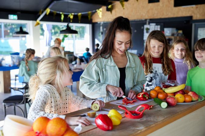 pedagogisch medewerker en kinderen in de bso maken gezonde snack  