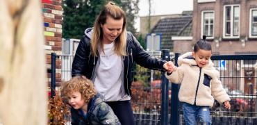 pedagogisch medewerker en twee jongentjes spelen buiten 