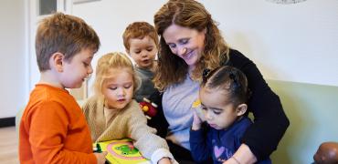 pedagogisch medewerker bekijkt prentenboek met kinderen 