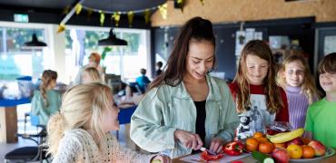 pedagogisch medewerker en kinderen in de bso maken gezonde snack  