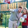Decoratieve foto van een coach Gezonde Kinderopvang. Hij wijst een kind met een bal een richting op.